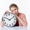 Sad beautiful young blond woman leaning on a clock