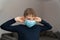 Sad boy in coronavirus quarantine removes a blue medical mask. Epidemic control of coronavirus and proper