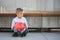 A sad boy holding a red moneybox and suitcase.