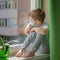 Sad boy in a medical protective mask wants to walk on the street, a child sits on the windowsill and yearns. Quarantine self-