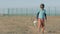 Sad boy orphan walking along the abandoned road with head down in the hands of holding a toy rabbit stopping and looking into the