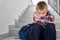 Sad boy of primary school sitting on stairwell.