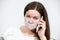 Sad brunette woman with cellphone and tape on her lips, grey background