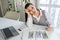 Sad business woman sits at work desk in front of laptop and counts cash. Concept of low salary