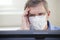 Sad businessman or doctor with face mask sitting behind a computer monitor in an office or  a hospital