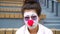 Sad clown with white face and red nose looking at camera