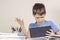 Sad, confused,surprised child with tablet computer sitting at table with books notebooks