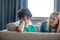 Sad curly boy sitting on sofa, blonde female talking to him, trying to cheer him up