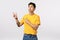 Sad cute asian male model in yellow t-shirt, pulling grumpy face, regret or miss something, pointing looking upper left