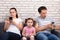Sad Daughter Sitting Between Parents Using Mobilephone