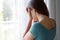 Sad depressed girl crying near the window at home in a rainy day, focus on model hand, indoor picture