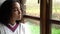 Sad depressed mixed race African American girl teenager young woman sitting looking out of a window