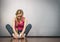 Sad depressed young teenage girl sitting by wall