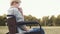 Sad disabled woman is sitting in field in wheelchair and is sad, thinking about future, touching face with hand. Closeup