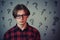 Sad and disappointed teenage boy, wearing red shirt and glasses, looking down displeased isolated on grey wall background. Upset