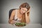 Sad displeased young woman eating salad