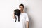 Sad dog owner crying, holding cute black pug on shoulder and looking miserable, sobbing while standing over white