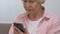 Sad elderly woman typing massage on smartphone, consulting with doctor online