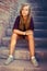 Sad girl with blue eyes sitting at stone brick stairs