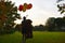 Sad girl child hugs a big teddy bear and balloons in the park. Schoolgirl unhappy in the park with a big toy and balls