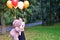 Sad girl child hugs a big teddy bear and balloons in the park. Schoolgirl unhappy in the park with a big toy and balls