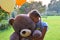 Sad girl child hugs a big teddy bear and balloons in the park. Schoolgirl unhappy in the park with a big toy and balls