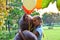 Sad girl child hugs a big teddy bear and balloons in the park. Schoolgirl unhappy in the park with a big toy and balls