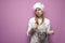 Sad girl cook in apron holds dishes and mixes food on a pink background, tired woman housewife holds kitchen items and looks at a