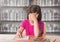 Sad girl at desk against bookshelves