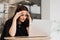 Sad girl with laptop got migraine touches her head because of pain. Woman manager with strong headache working on laptop