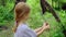 A sad girl looks at a flower plucked by her in the middle of the forest.