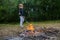 The sad  girl makes fire in the forest for cooking.  Family leisure with kids at summer