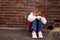 Sad girl sitting against brick wall