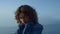 Sad girl standing on ocean beach. Distressed woman touching neck with hands