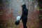 Sad girl walking in dark clothing in autumn forest, with balloons, black and white. Concept of choice, good and evil