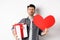 Sad and heartbroken man being rejected, crying and holding red heart with gift box, breakup on Valentines day, white