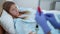 Sad ill teenage girl lying in hospital ward with nurse hands adjusting dropper. High angle view portrait of devastated