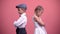 Sad kids couple standing back in silence after quarrel, isolated pink background