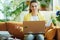 Sad learner woman in modern house in sunny day study online