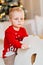 sad little boy with bruise under eye in red Christmas sweater on rocking horse