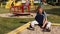sad little boy with a fractured limb outdoors. a child with broken arm is sitting by the playground and touching plaster