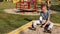 sad little boy with a fractured limb outdoors. a child with broken arm is sitting by the playground and touching plaster