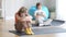 Sad little girl hugging knees sitting on exercise mat as blurred confident boy in lotus pose training at background