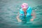 A sad little girl in a life jacket tries to swim in the ocean. Portrait of a frightened child in the sea. A baby is saved after a