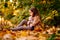 Sad little girl sitting on ground in fallen leaves. children`s resentment