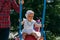 Sad, little girl in a white dress and hat, riding on a swing, summer sun and heat. playground. childhood, serenity. negative