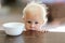 Sad Little One Year Old Baby Girl with Empty Cereal Bowl