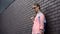 Sad lonely student with school backpack in eyeglasses standing campus wall