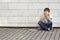 Sad, lonely, unhappy, disappointed child sitting alone on the ground. Boy holding his head, look down. The tablet pc