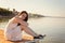 Sad lonely young woman sitting hugging her knees on the pier with sad eyes, loneliness, separation, apathy, depression